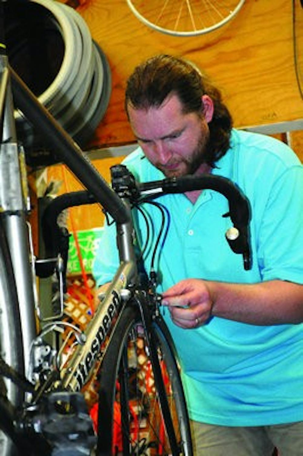 Daniel Trouse, manager of The Bike Shop, works on one of the bikes in the store. (Christen Harned / ASSISTANT PHOTO EDITOR)