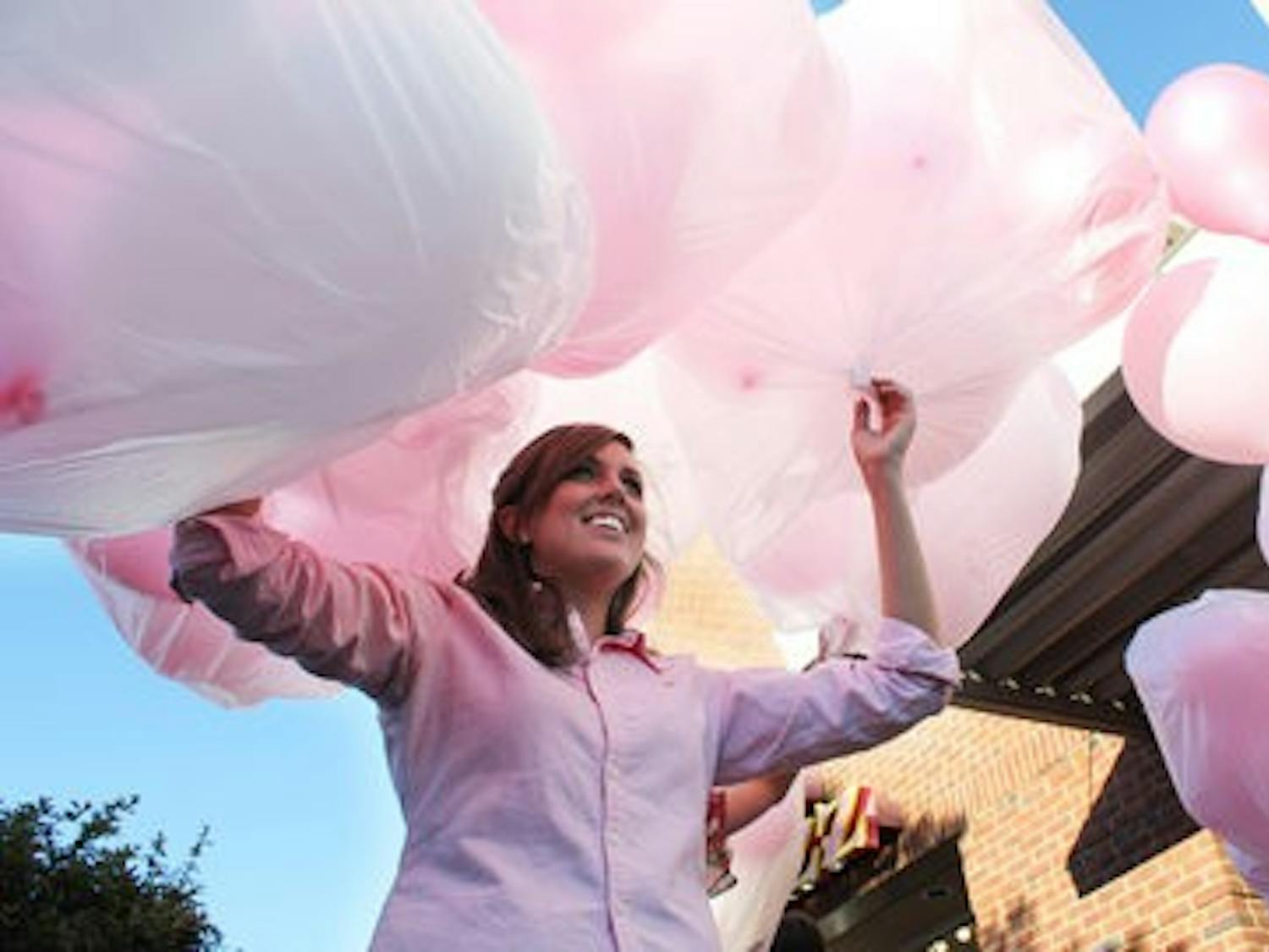 Katie Hicks, store manager, carries bags of pink balloons to be released  into the skies of downtown Opelika Friday. (Emily Adams / Photo Editor)