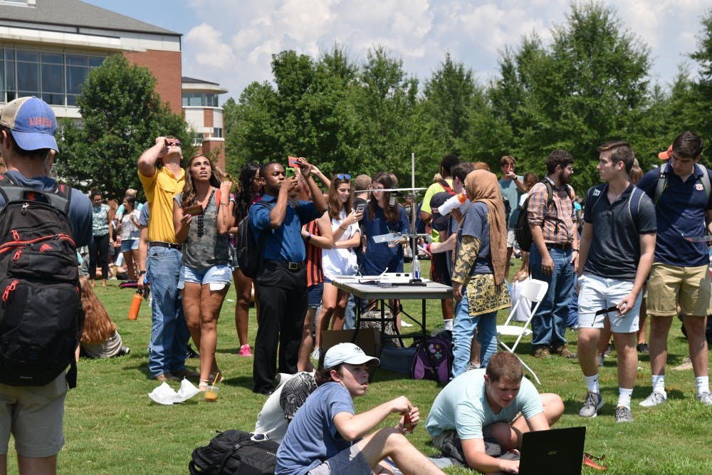 Students gathered on the green space to look to the sky.