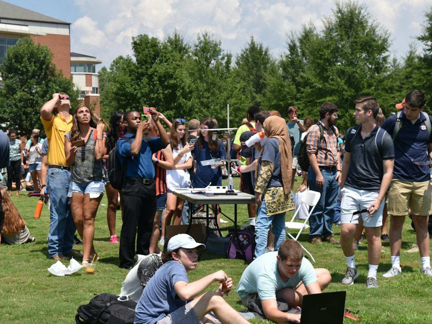 Students gathered on the green space to look to the sky.