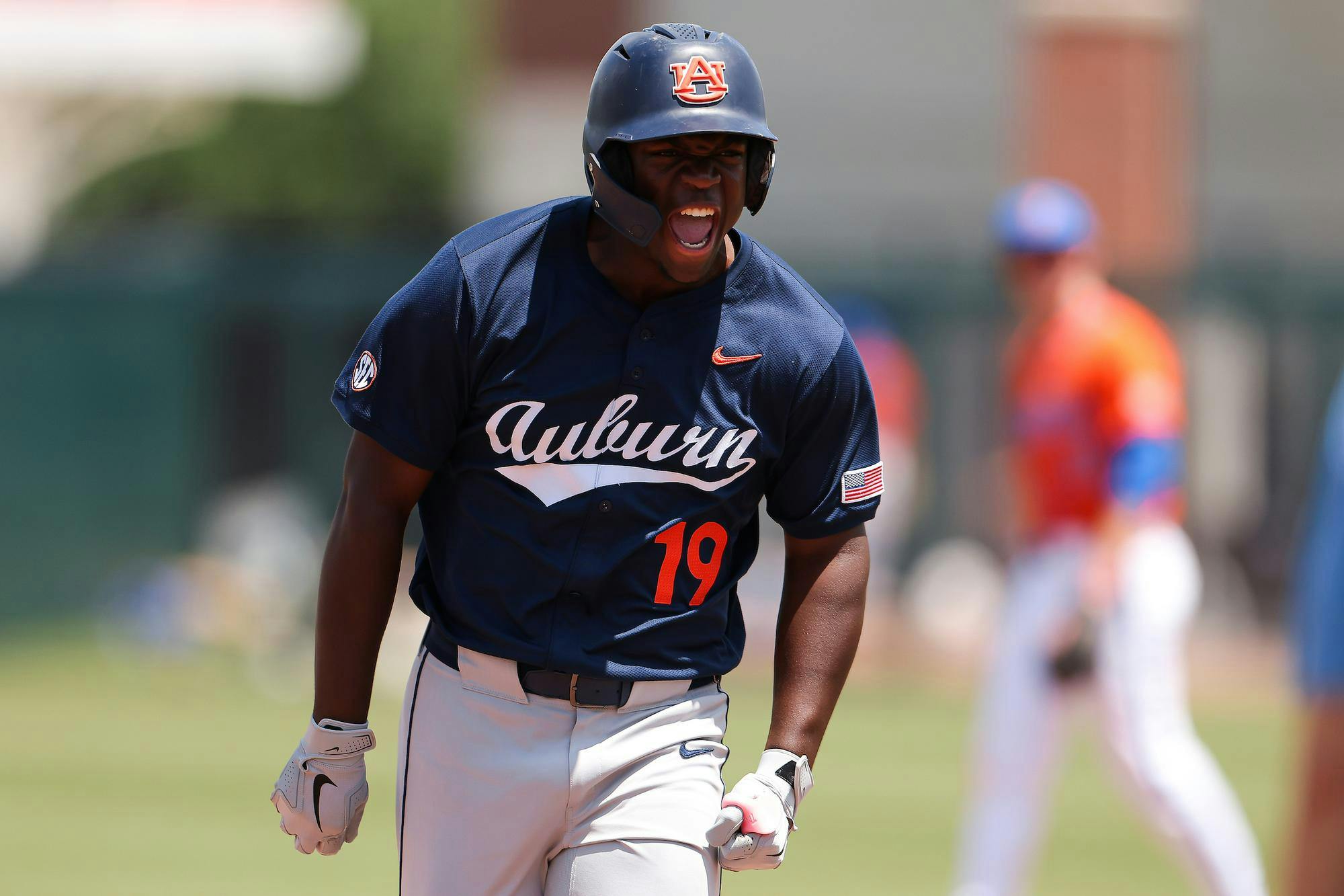 A baseball player wearing a dark blue jersey with "Auburn" displayed prominently celebrates energetically on the field.