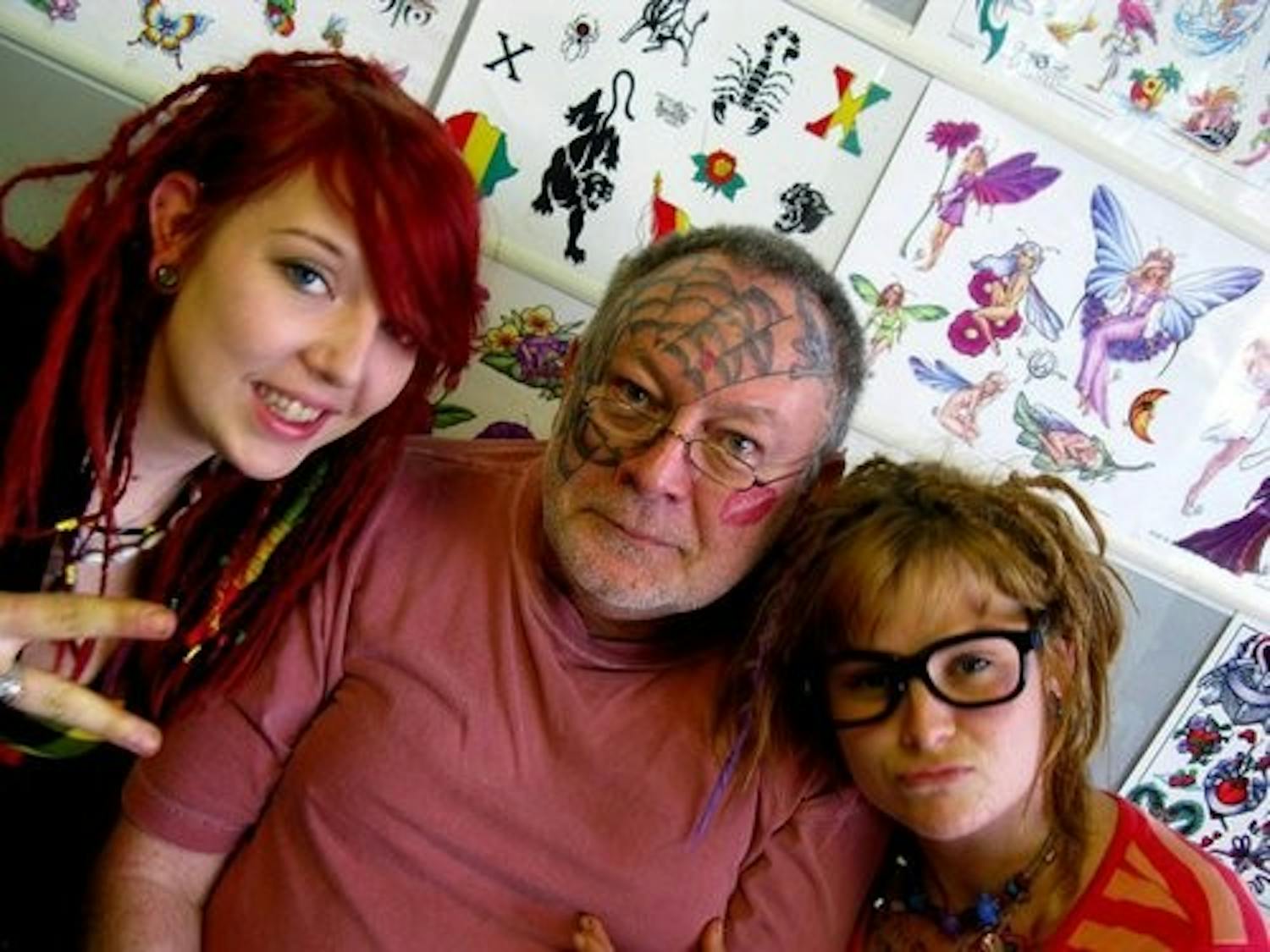 Opelika resident Rick Braggett (center) got his full-face tattoo at the Voodoo Needle. Tattoo artist Erik Javor worked on Braggett's first face tattoo spider web and later added the lipstick kiss on Braggett's left cheek. (Kendall Wangman / WRITER)