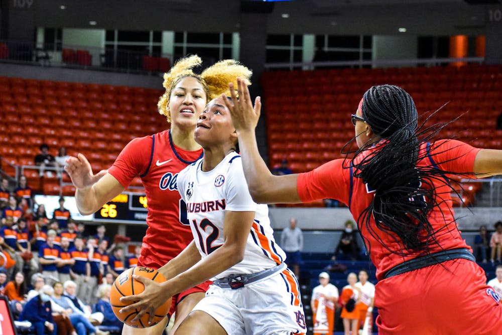 <p>Mar'shaun Bostic (12) drives a line between two defenders in a match between Auburn and Ole Miss in the Auburn Arena on Feb. 24, 2022.</p>