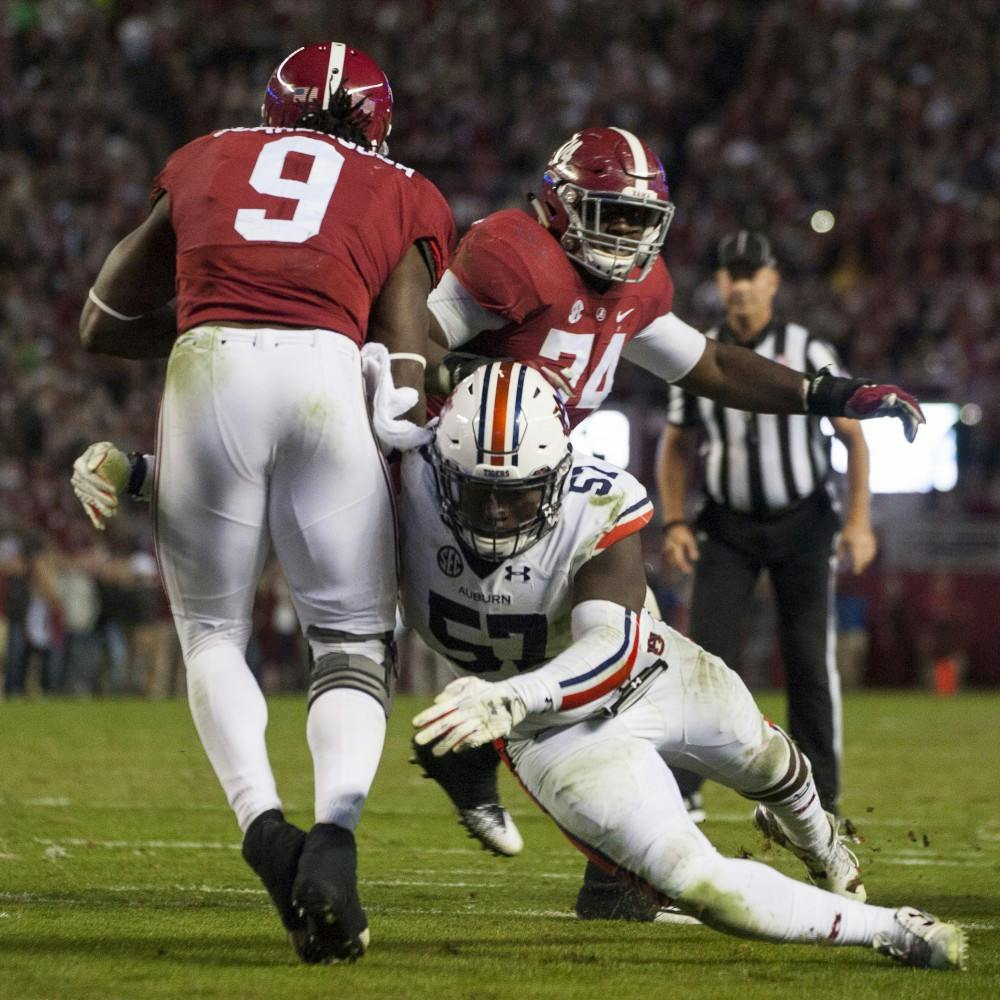 Deshaun Davis (57) tackles Alabama's Bo Scarbrough (9) in the second half. Auburn vs Alabama on Saturday, Nov. 26 in Tuscaloosa, AL.