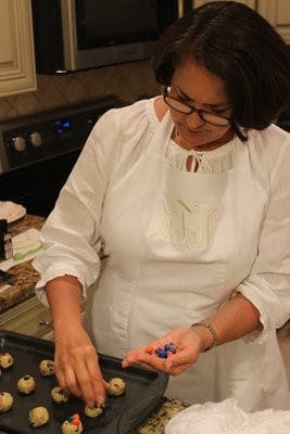 Cindy Thrash decorates homemade cookies with orange and blue candies.