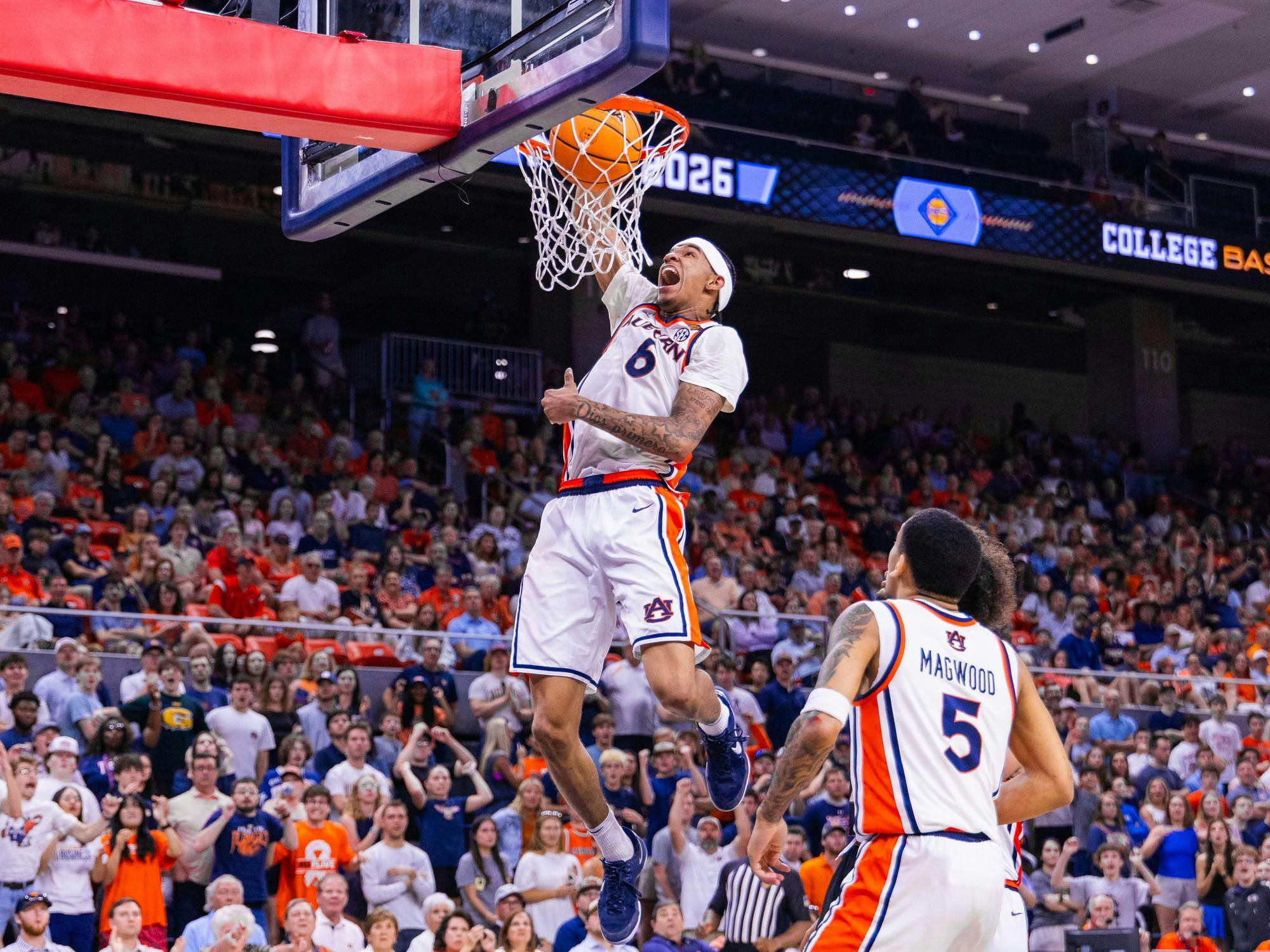 A basketball player leaps towards the hoop, ready to dunk as excited fans cheer in the crowded arena.