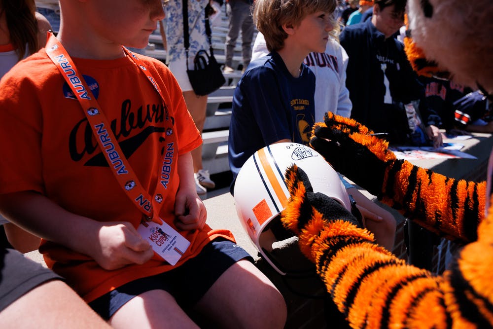 Aubie autographs a kid's football helmet during A-Day, Saturday April 12, 2025.