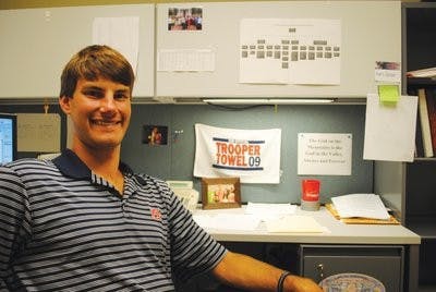 Hard at work and ready to serve, SGA President Kurt Sasser displays his signature grin in front of his desk. Sasser beat his opponent Brad Cink last semester in a run-off election. (Maria Iampietro / AssOCIATE PHOTO EDITOR)