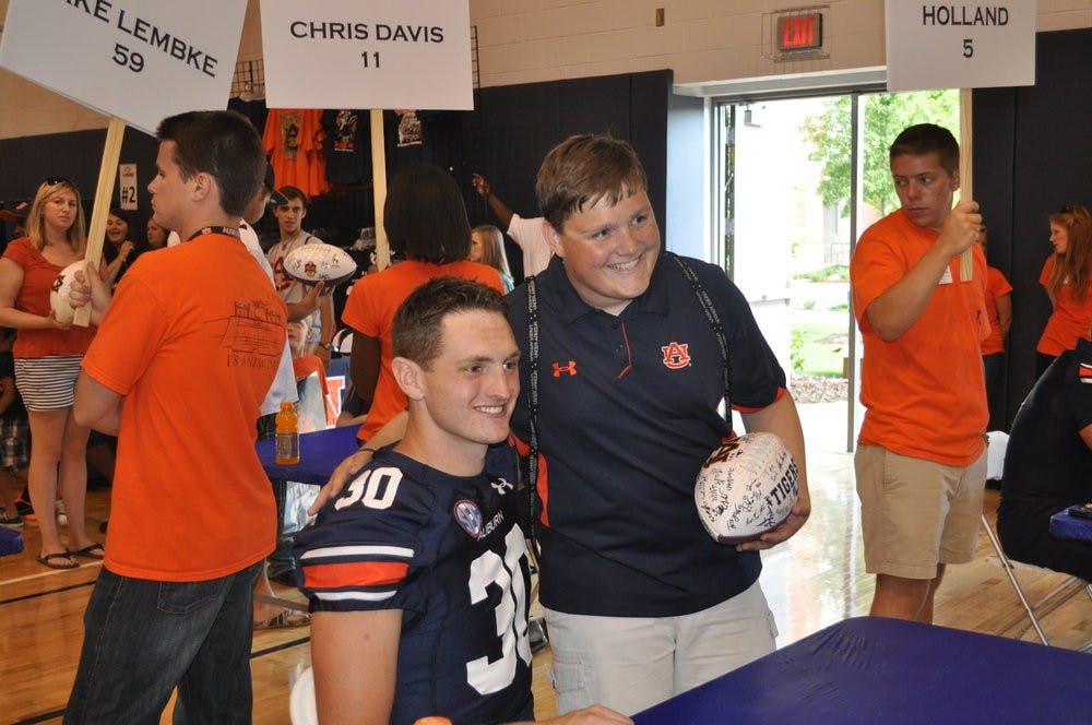 <p>Punter Steven Clark takes a photo with a fan after signing autographs on Fan Day 2013. Anna Grafton / ASSOCIATE PHOTO EDITOR</p>