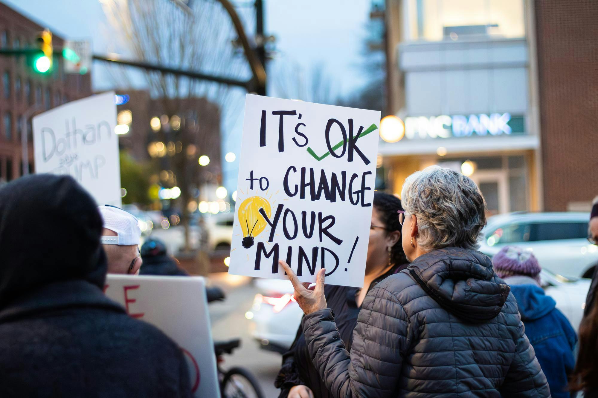 A protestor at the ICE, Immigration and Customs Enforcement, protest on Jan. 21, 2026 at Toomer's Corner in Auburn, Ala. holds a sign that says 'It's OK to change your mind!'.