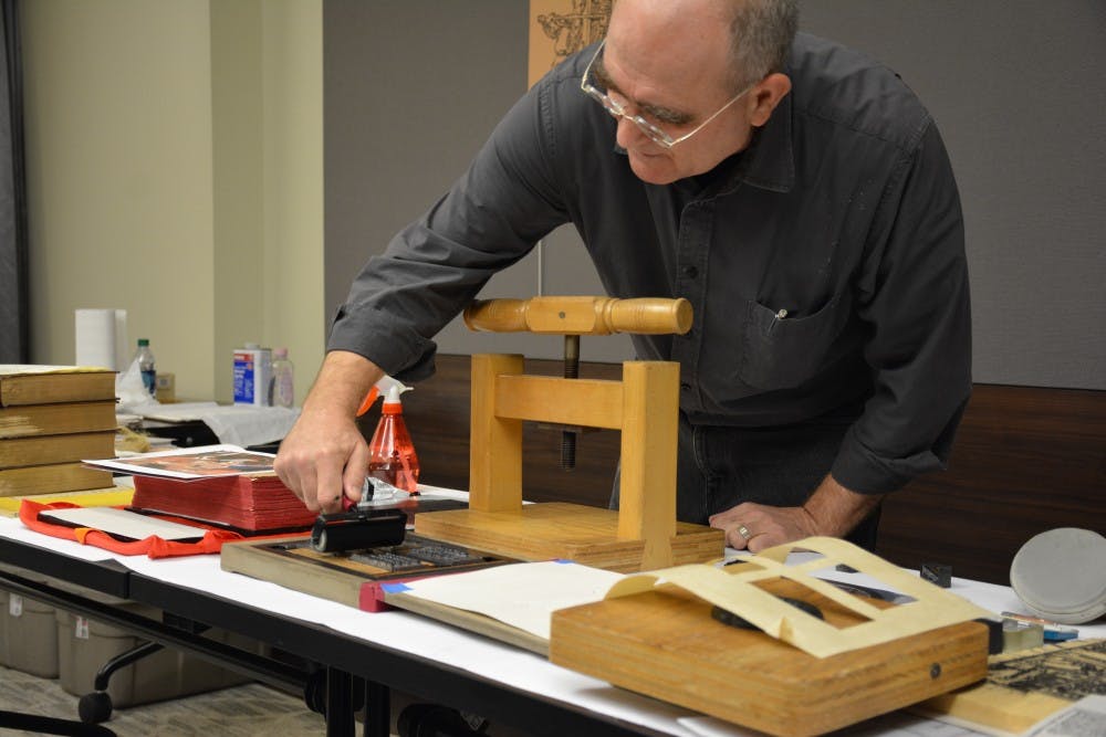 Josef Beery demonstrates how to use a platen press, made out of a repurposed flour press.&nbsp;