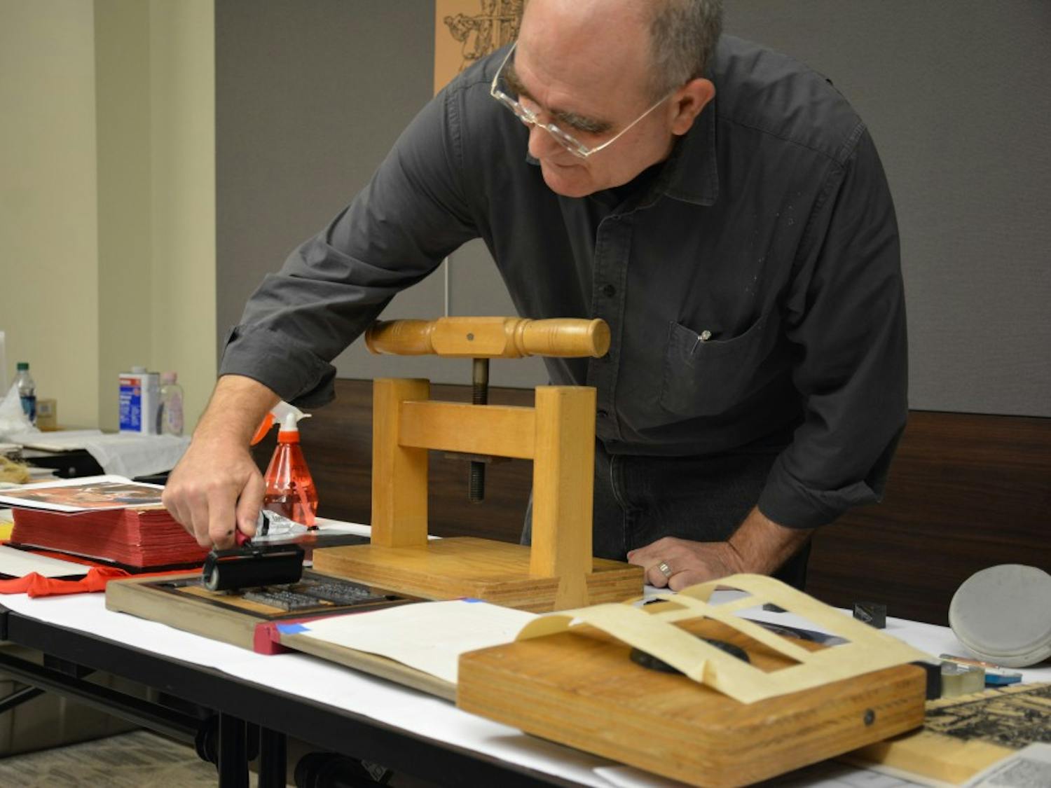 Josef Beery demonstrates how to use a platen press, made out of a repurposed flour press.&nbsp;