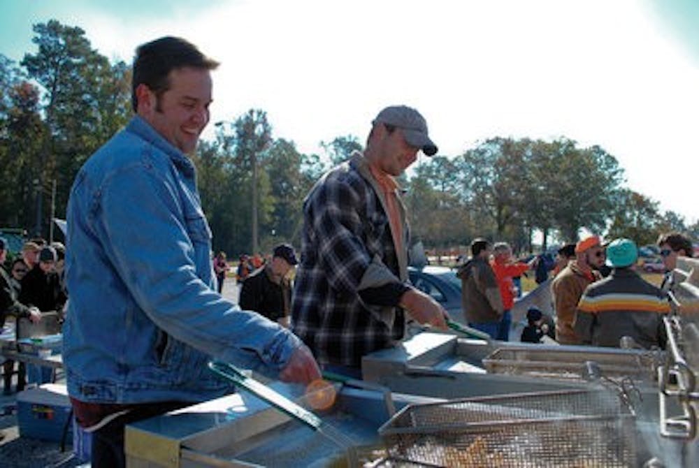 Corey Courtwright and Jeremy Pickens, Ph.D. students in fisheries, fry catfish for visitors at the 31st annual Ag Roundup Nov. 6 before the homecoming game. The event's proceeds contribute to scholarships within the college. ( Maria Iampietro / Associate Photo Editor)