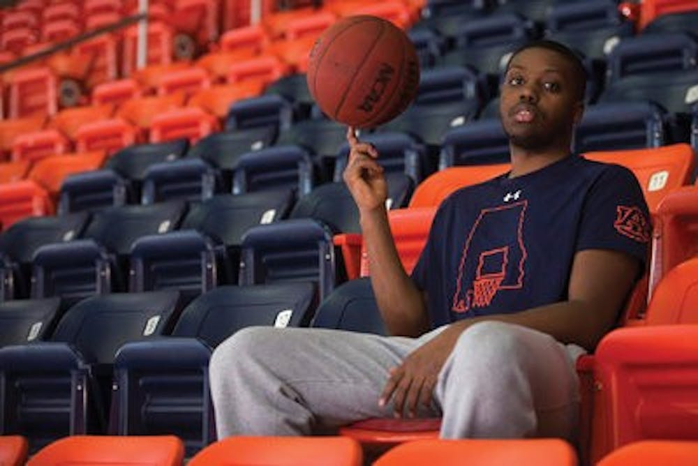 <p>Senior guard Malcolm Canada spins a basketball on his finger in the Auburn Arena. Canada said he relied upon friends and family to help him after his father's arrest. (Zach Bland | Contributing Photographer)</p>