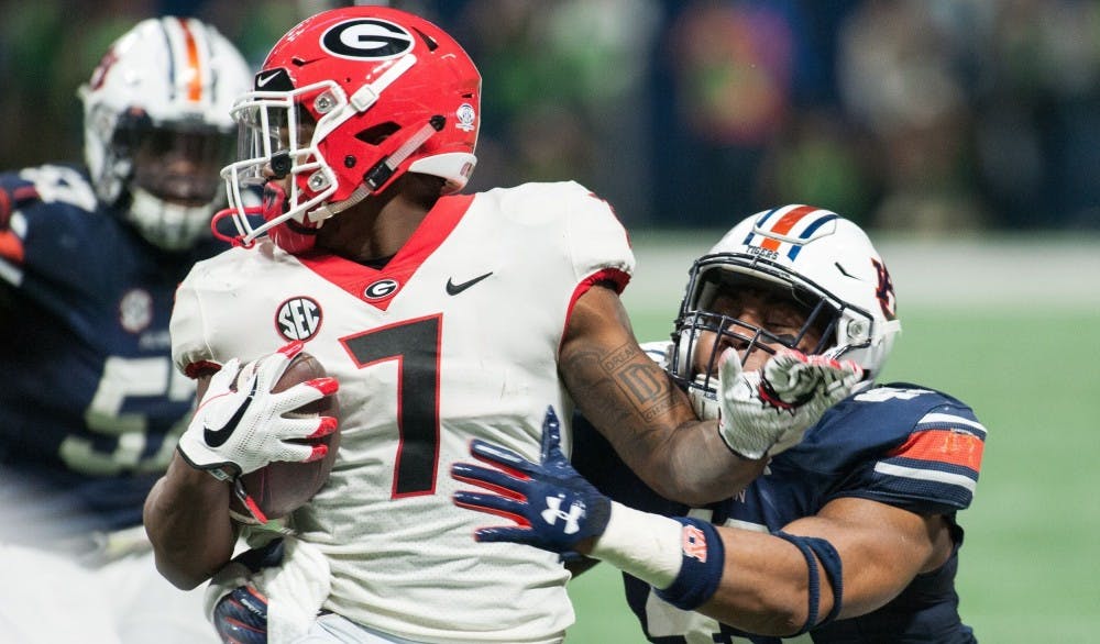 <p>D'Andre Swift (7) spins away from the tackle of Darrell Williams (49) in the second half. Auburn vs Georgia in the SEC Championship Game on Saturday, Dec. 2 in Atlanta, Ga.</p>
