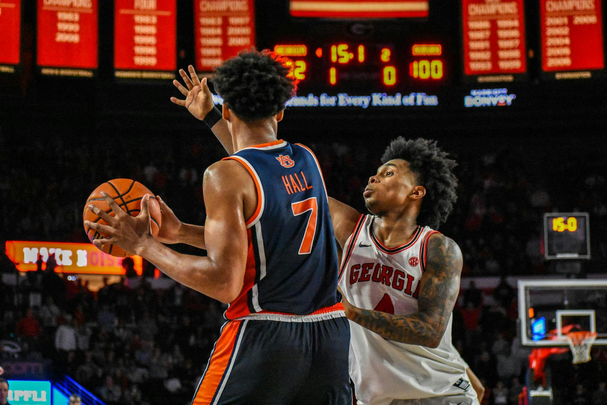 Two basketball players are in action on the court, one holding a ball and the other defending closely.