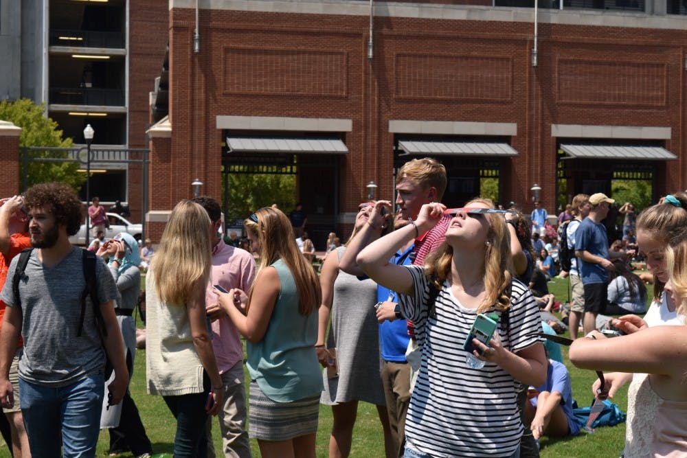 Students gathered on the green space to look to the sky