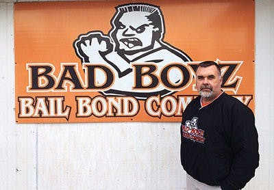 Corey Marmaduke stands in front of his Bad Boyz Bail Bond Company logo