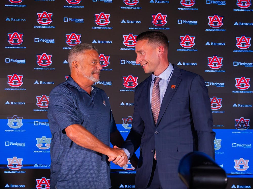 Auburn basketball Head Coach Steven Pearl (right) shakes hands with his father, and former Auburn Head Coach Bruce Pearl (left), during Steven Pearl's introductory press conference on Sept. 24, 2025.