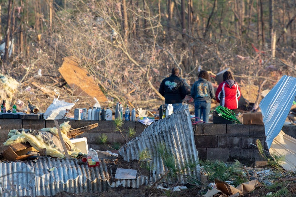 Residents stand together on March 4, 2019, alongside the wreckage of a home completely destroyed by a tornado that killed 23 people in Beauregard, Alabama, the previous day.