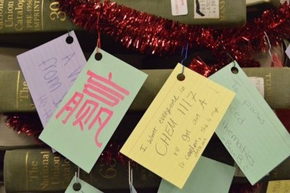 Students were encouraged to grab a colored index card, write a holiday wish and hang it on the red tinsel wrapping the book tree. (Emily Enfinger | Assistant Photo Editor)