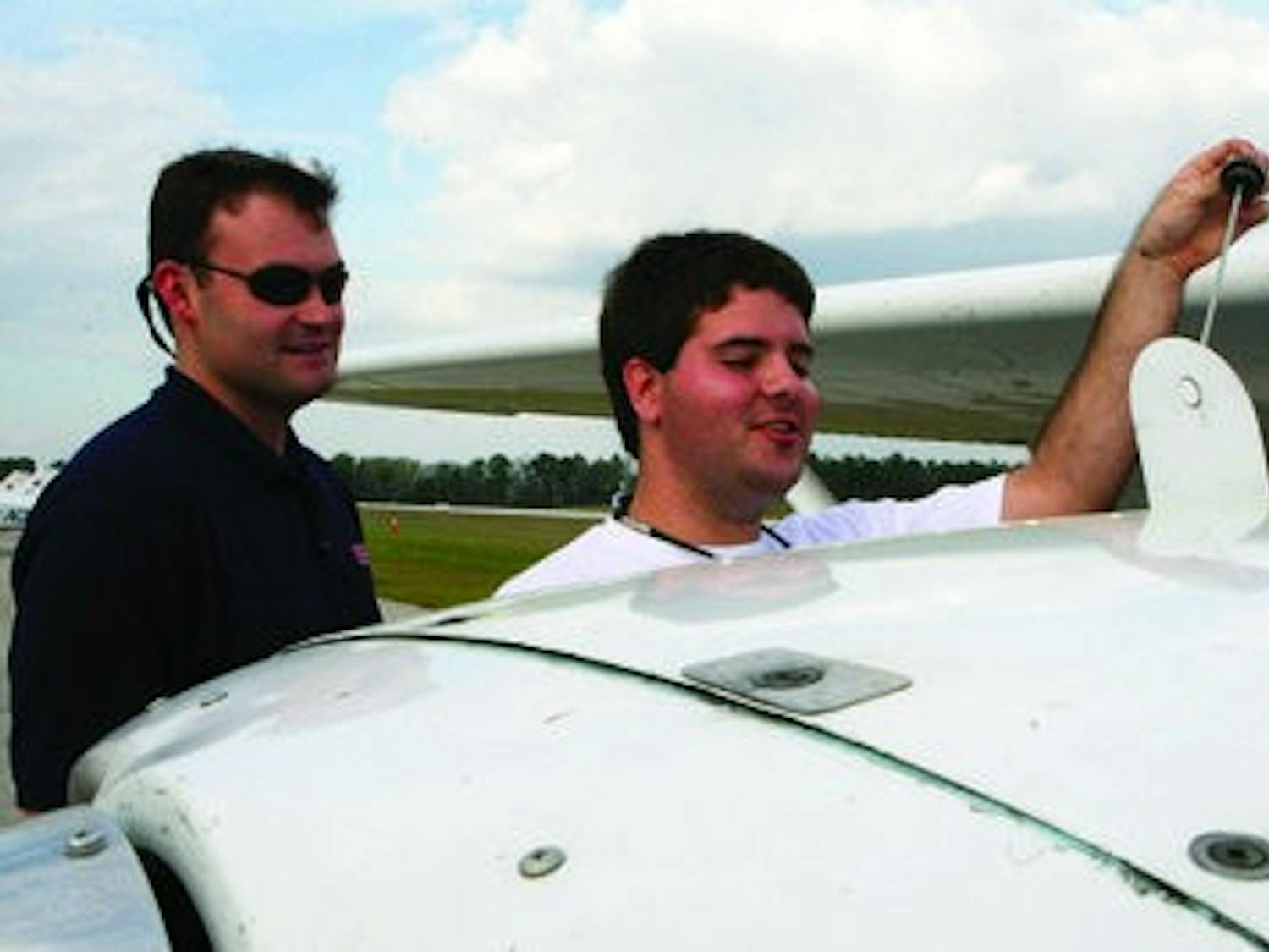 Joe McDonald, right, senior in aviation management, checks the oil of a single-engine propeller plane with instructor Matt Jones. Auburn Aviation offers discounted starter lessons to those interested in earning their wings. (Rebecca Croomes / PHOTO EDITOR)