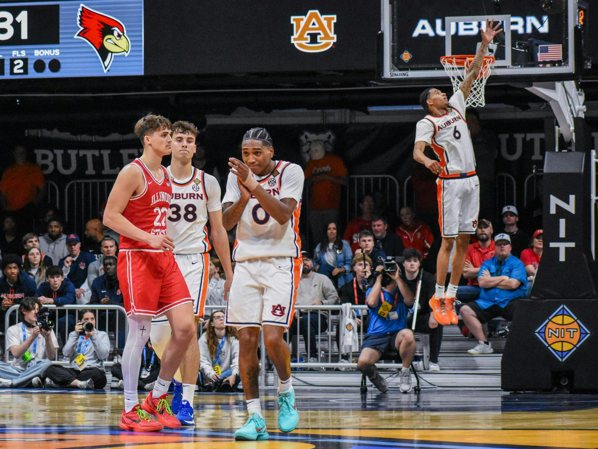 A basketball game shows players from Auburn and Illinois State, with one athlete jumping to make a shot while others react.