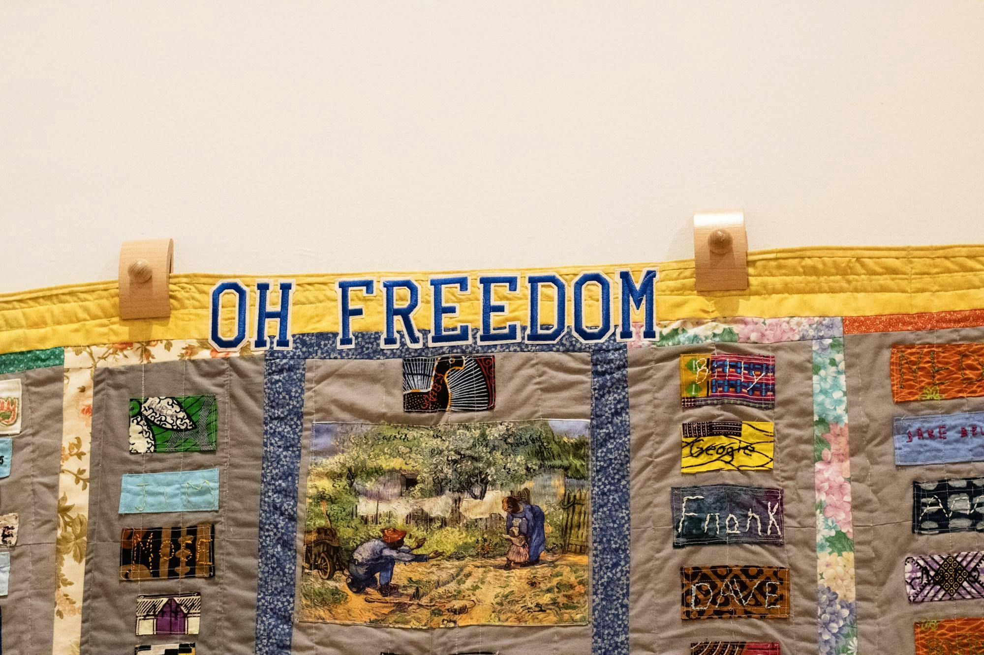 A quilt features colorful patches and a central image, with the words "OH FREEDOM" prominently displayed at the top.