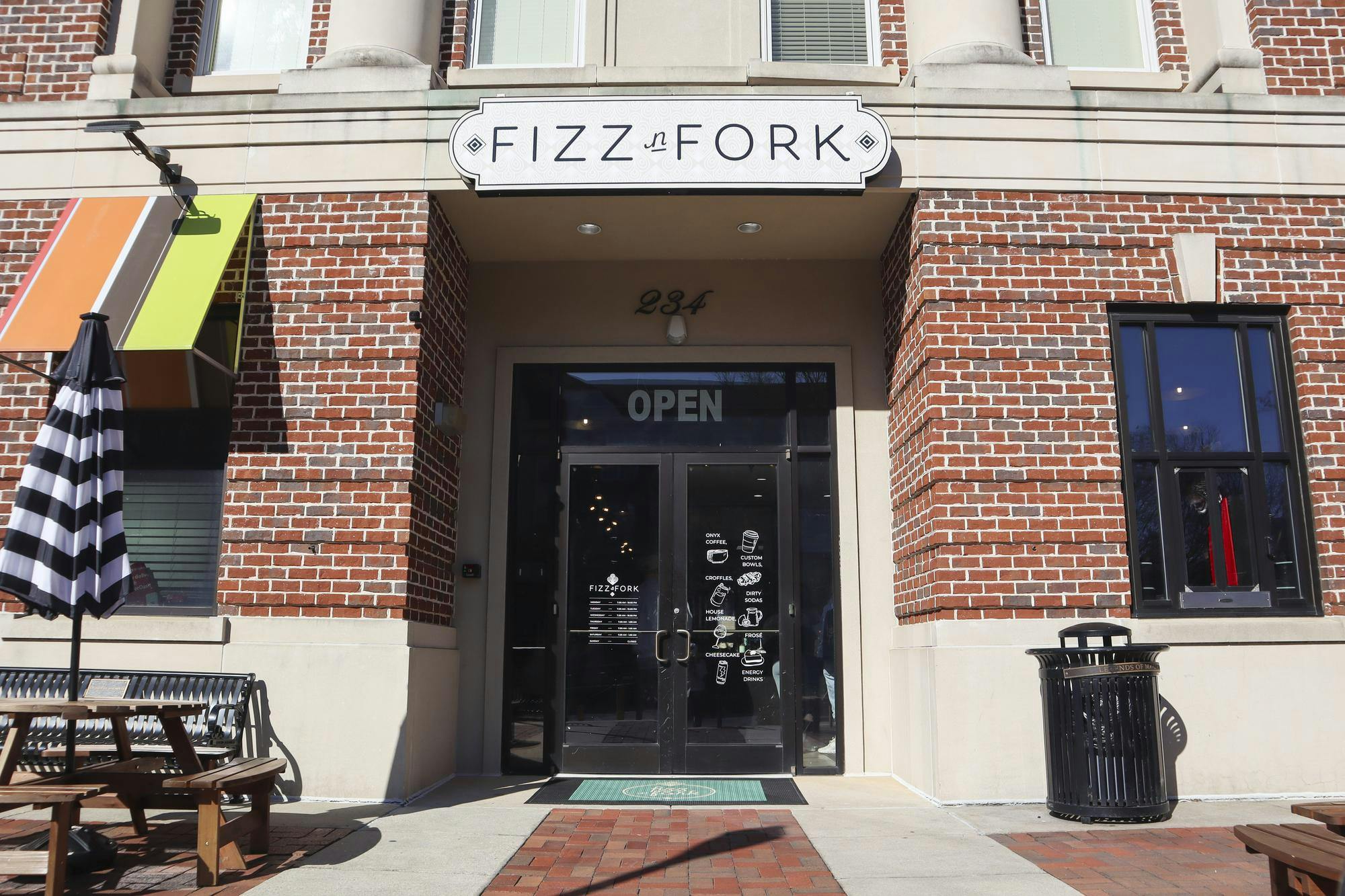 A brick storefront features a glass door with "OPEN" signage and a sign reading "FIZZ n FORK" above.