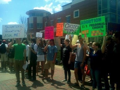 Opponents to the abortion display protest opposite the massive signs. (Raye May / PHOTO EDITOR)