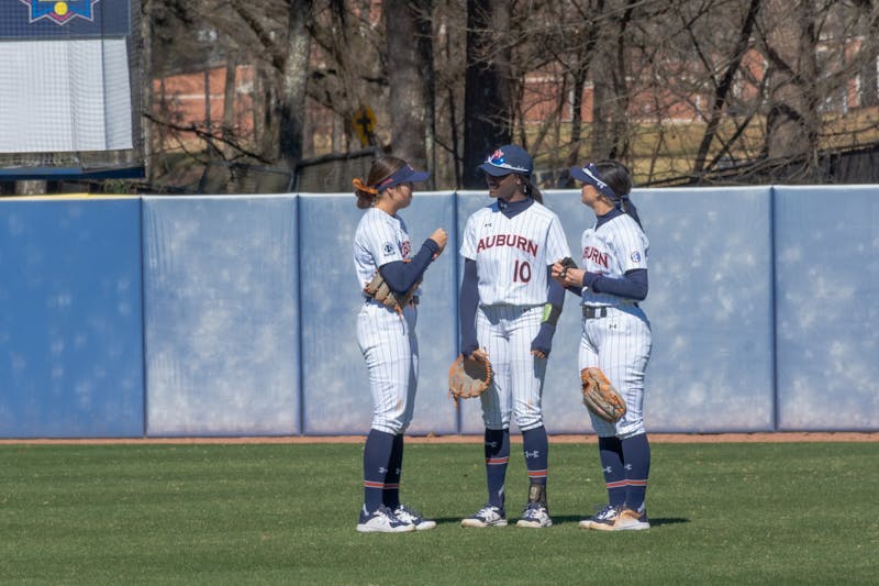 Feb. 13, 2022; Auburn, Ala; Carlee McCondichie (left), Makayla Packer (center) and Lindsey Garcia (right) talk in the outfield during a break in the action against UMass Lowell in the Tiger Invitational.