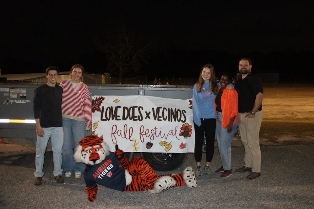 <p>Love Does in Action members pose with Aubie the Tiger in front of a sign for the fall festival hosted with Vecinos Ministry. Contributed by Love Does in Action.</p>