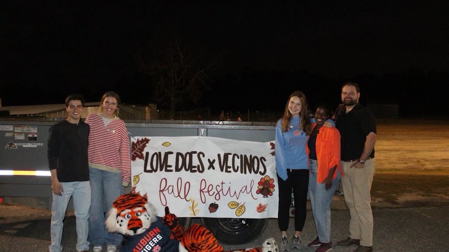Love Does in Action members pose in front of a sign for the fall festival hosted with Vecinos Ministry. Contributed by Love Does in Action.