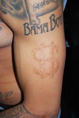 Voodoo Needle tattoo artist Henry Key shows a close-up of his dollar-sign brand.