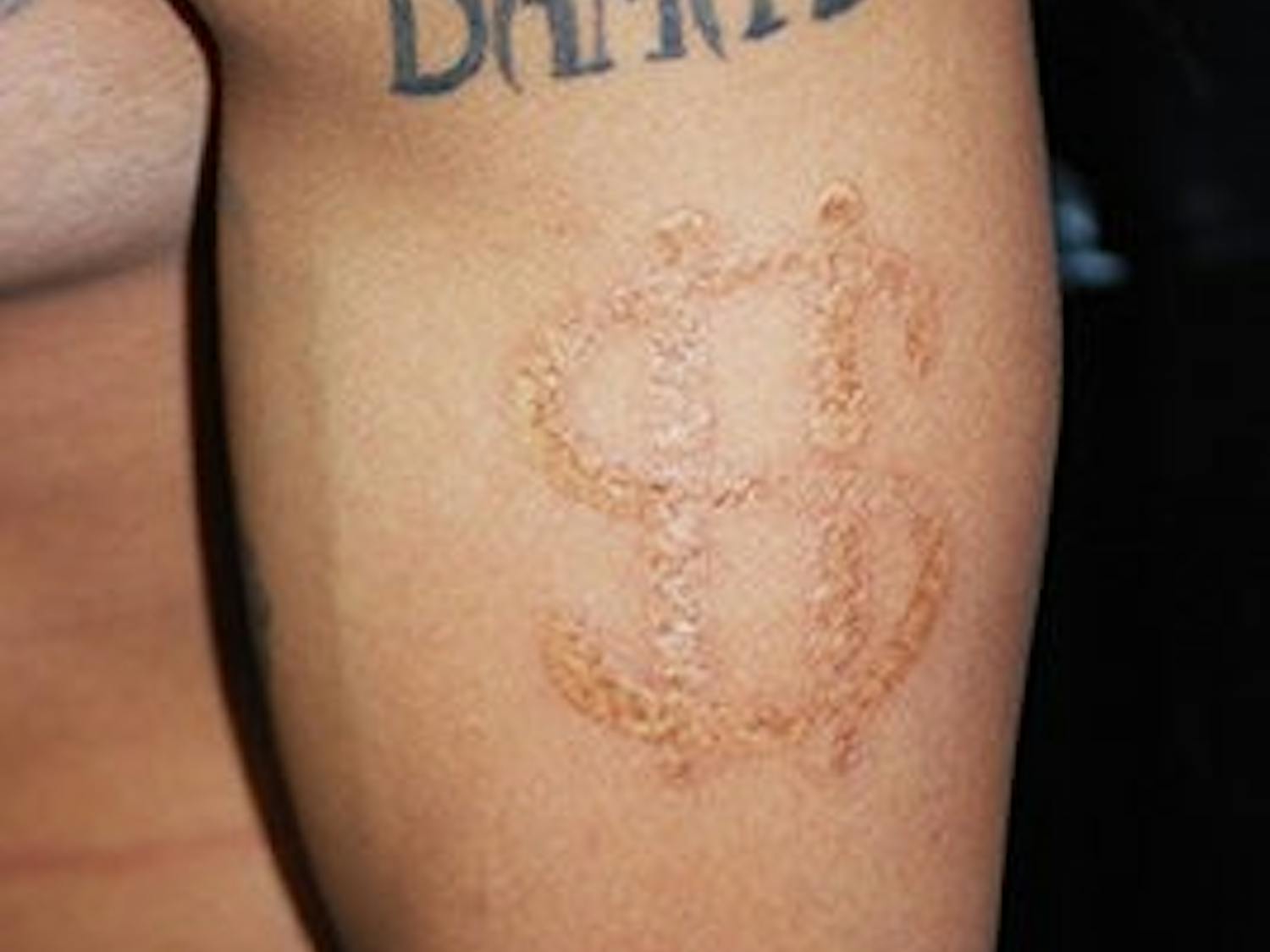 Voodoo Needle tattoo artist Henry Key shows a close-up of his dollar-sign brand.