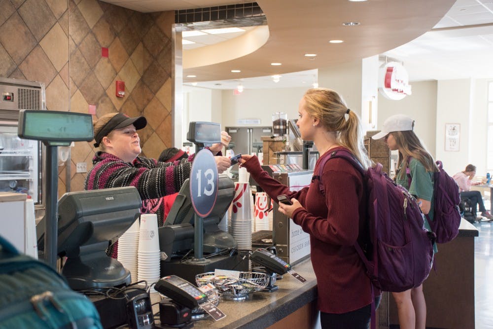 <p>A student gives her Tiger Card to the cashier at the on-campus Chick-fil-A on Wednesday, 11, 2018, in Auburn, Ala.</p>
