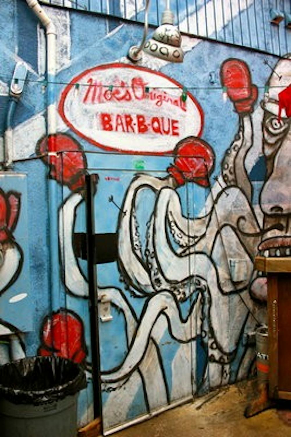 <p>The murals Christian Hamrick painted at Moe's Bar-B-Que are funky, one-of-a-kind anecdotes that cover the brick walls on the inside of the restaurant and outside on the back patio. (Courtesy of Chelsea Wooten)</p>