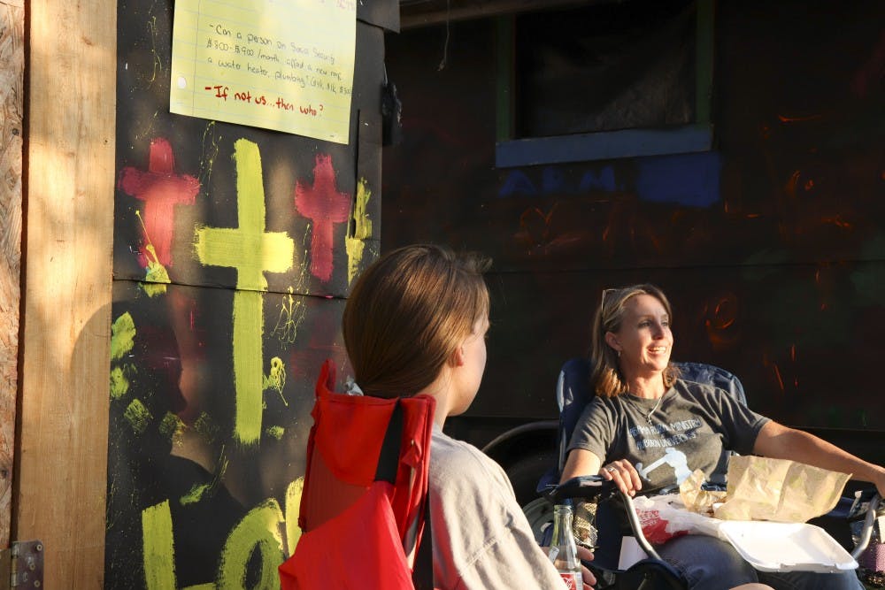 <p>Lisa Pierce visits with a guest outside of Wesley Foundation at her shack in Auburn on Oct. 15, 2018.</p>