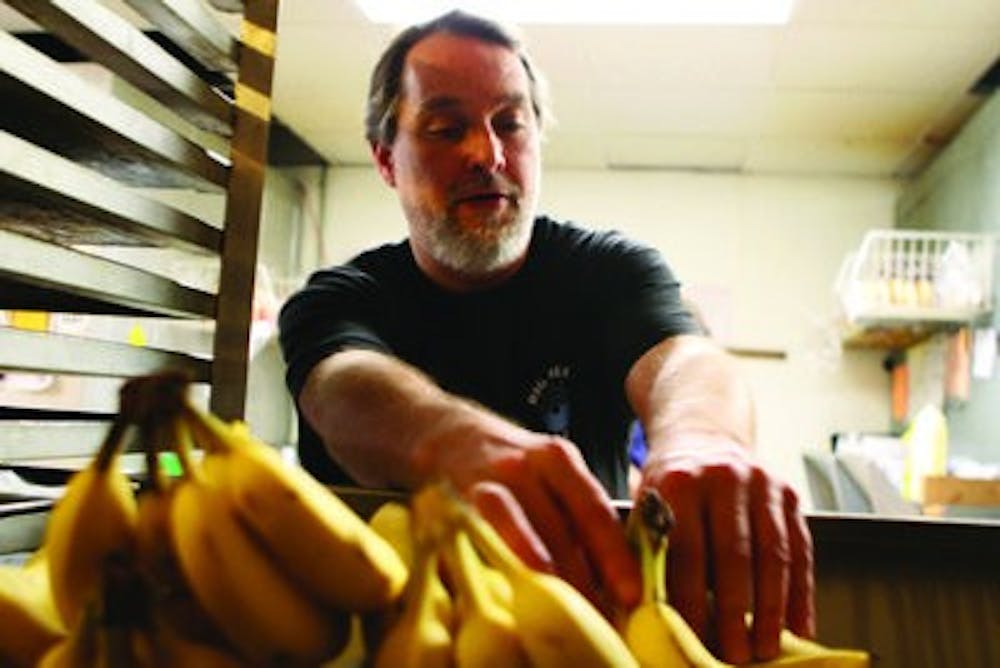 Jon Deason, owner of Big Blue Bagel on South College Street, grabs a banana to slice up for fruit salad. Deason also owns a Big Blue Bagel in Birmingham. (Rebecca Croomes / PHOTO EDITOR)