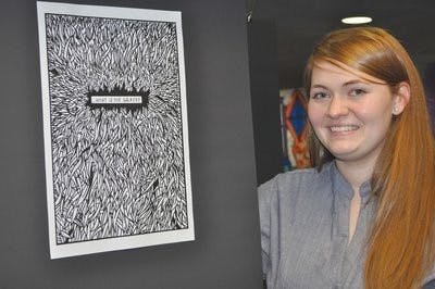 Artist Kristi Dallen poses in front of a frame from her interactive exhibit "Uncle Walt" at the Layman Group loft Friday. (Christen Harned / Assistant Photo Editor)