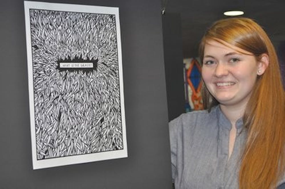 Artist Kristi Dallen poses in front of a frame from her interactive exhibit "Uncle Walt" at the Layman Group loft Friday. (Christen Harned / Assistant Photo Editor)