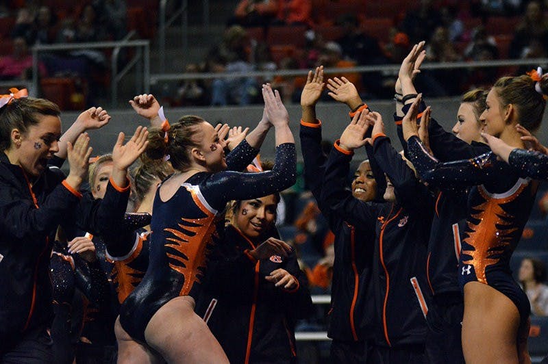 Caitlin Atkinson celebrates with team after successful routine on the beam. Auburn Gymnastics vs Arkansas in Auburn, AL on Jan 23, 2015. Emily Enfinger | PHOTO EDITOR