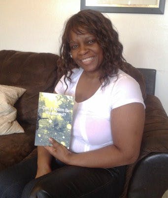 Tangela Johnson sits in her home with her book "Can a Storm be Weathered? Memoirs of a Broken Past."