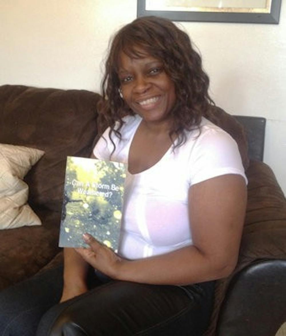 Tangela Johnson sits in her home with her book "Can a Storm be Weathered? Memoirs of a Broken Past." (Anna Claire Conrad / Copy Editor)
