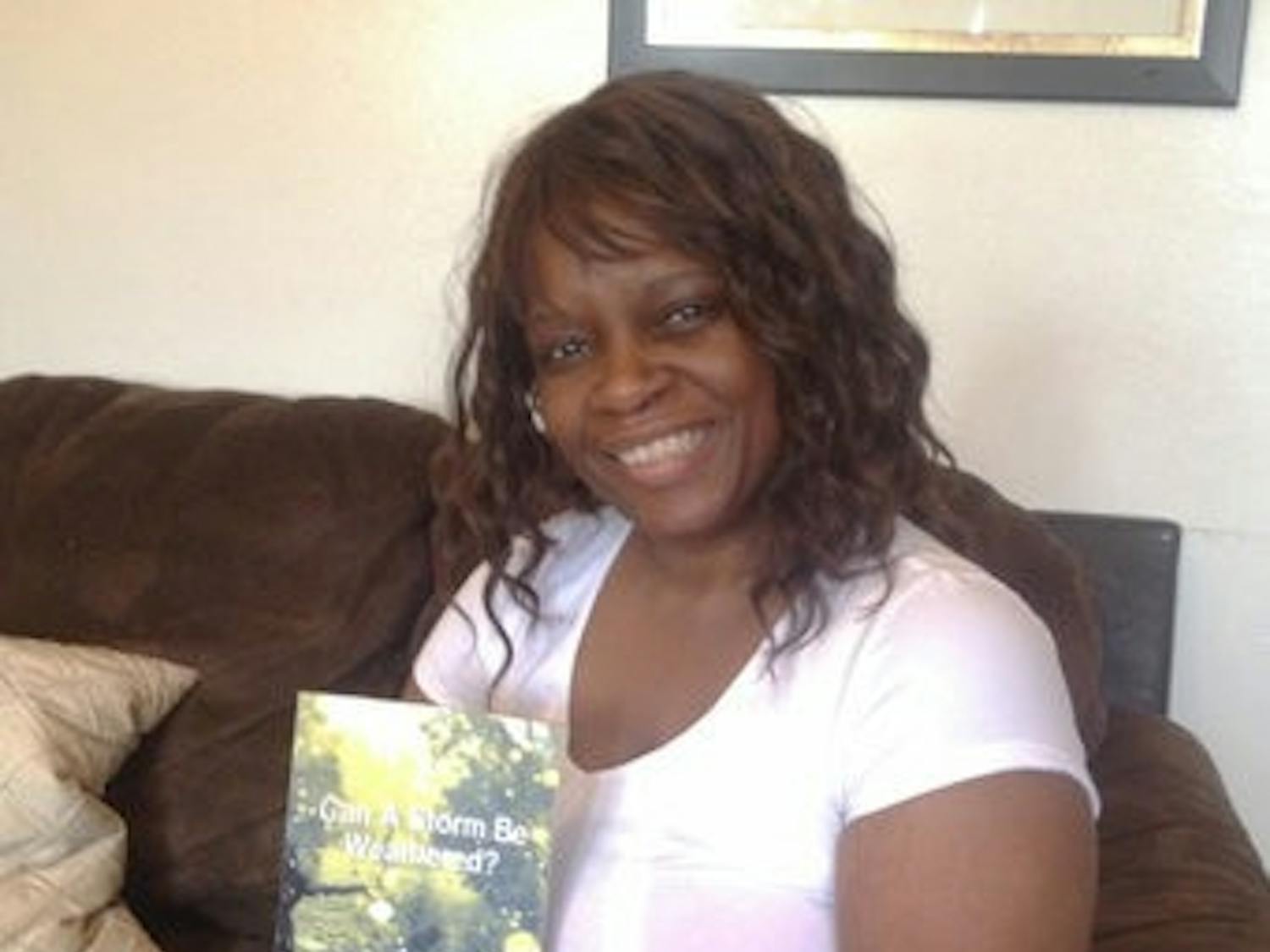 Tangela Johnson sits in her home with her book "Can a Storm be Weathered? Memoirs of a Broken Past."
