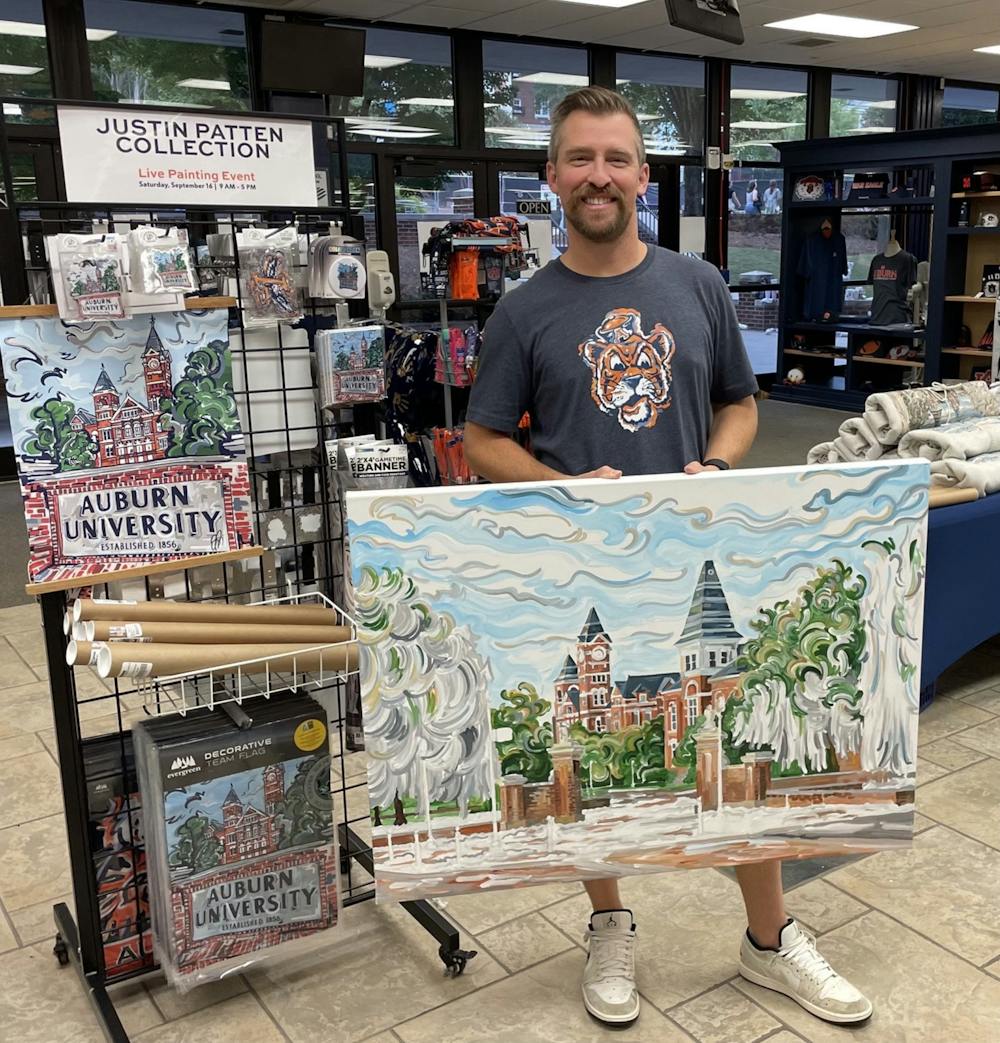 Justin Patten at the Auburn University Bookstore holding his painting of Samford lawn after a win on game day. 