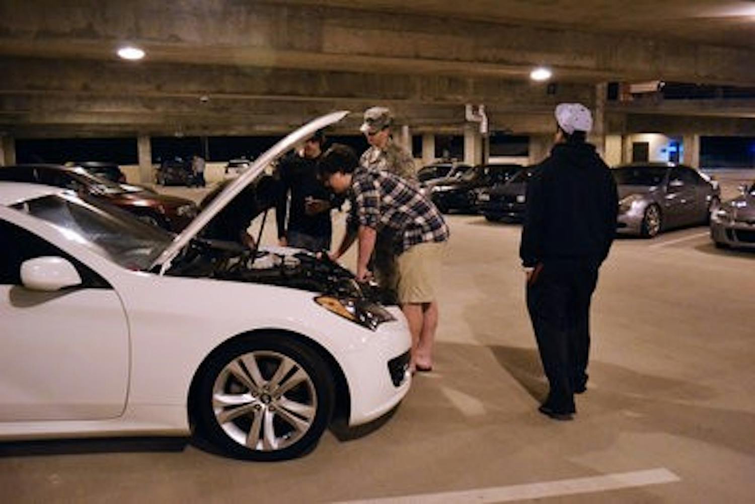 Ryan Flannery, freshman in mechanical enginnering, examines his car with fellow AUCtane members at their meeting in the South Quad parking deck Tuesday night. (Danielle Lowe / ASSISTANT PHOTO EDITOR)