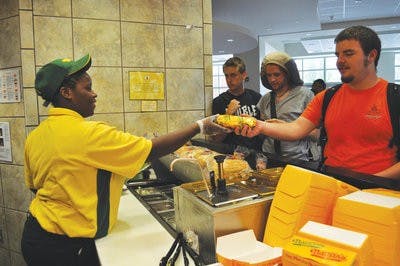 Qunekka Dowdell hands a Philly cheesesteak to Matthew Hardwick, junior in software engineering, at Nathan's Famous in the Student Center, Tuesday afternoon. Satisfatcion awaits. (Christen Harned / Asisstant Photo Editor)