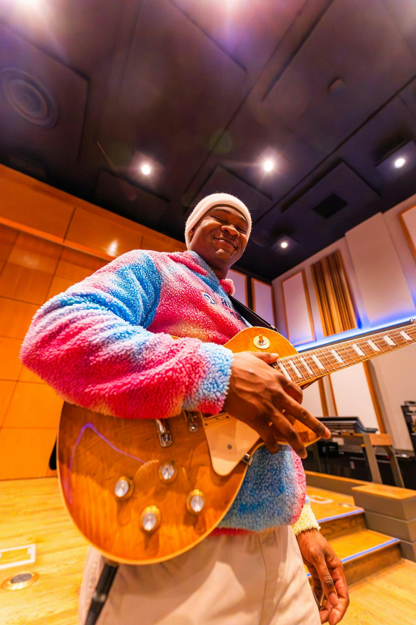 Student musician Walter Lloyd stands happily with guitar.