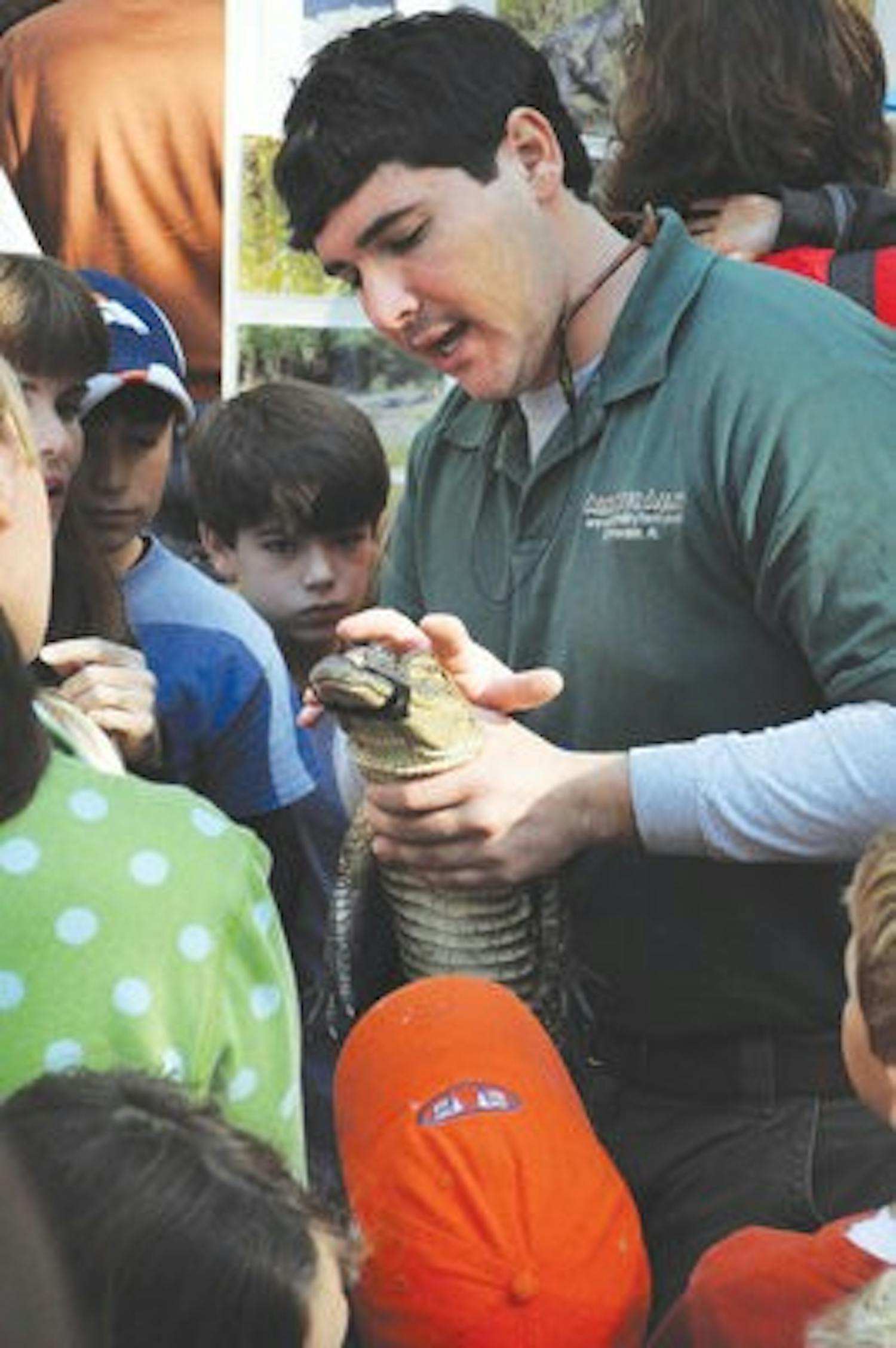 Evan Wheeler from Alligator Alley shows a live alligator to a crowd of children at the Ecology Preserve Oct. 30. (Christen Harned / ASSISTANT PHOTO EDITOR)